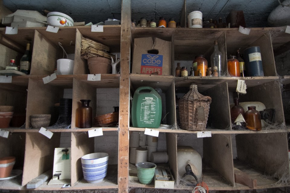 Petrol cans, gardening utensils and storage containers line the garage wall