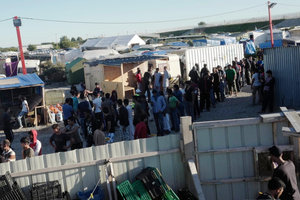  Migrants queue in the Calais camp to receive their daily food handouts