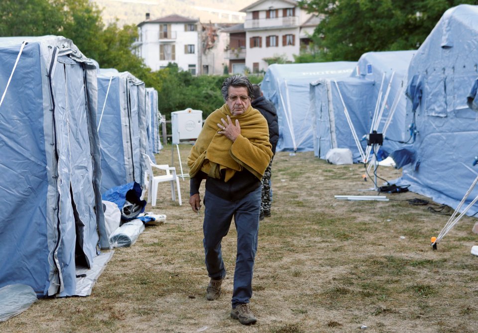 A man walks along a makeshift camp in Arquata