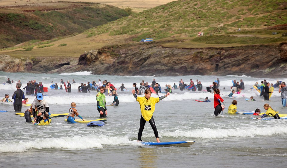  Surfers ride the waves in Polzeath in Cornwall