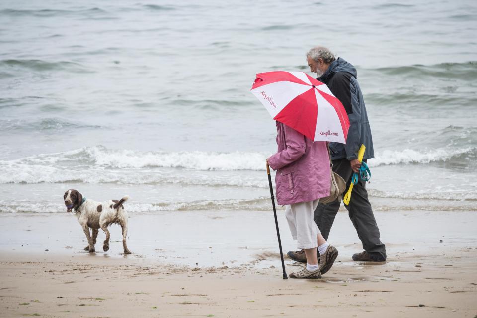  A couple take the dog for a walk on a wet Thursday morning at Saltburn on the North Yorkshire coast. A bit of a north south divide on Thursday in the UK, with much of the south enjoying warm sunshine