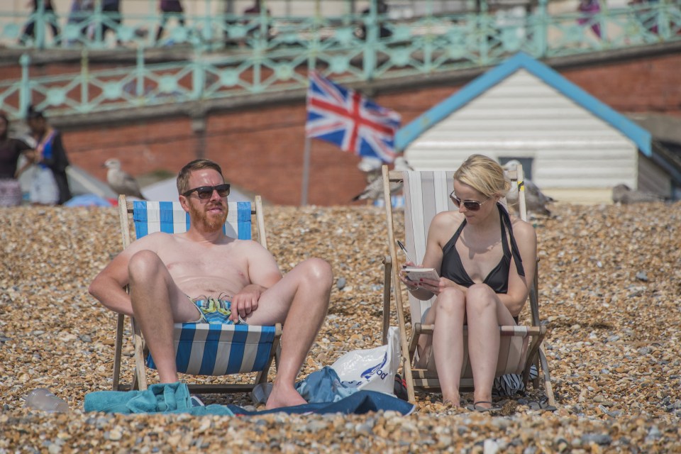  People on the beach enjoy the seasonal weather in Brighton as the UK braces for a washout bank holiday