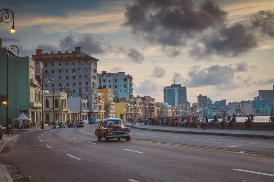 A red vintage car drives along the Malecon, Havana's main coastal road