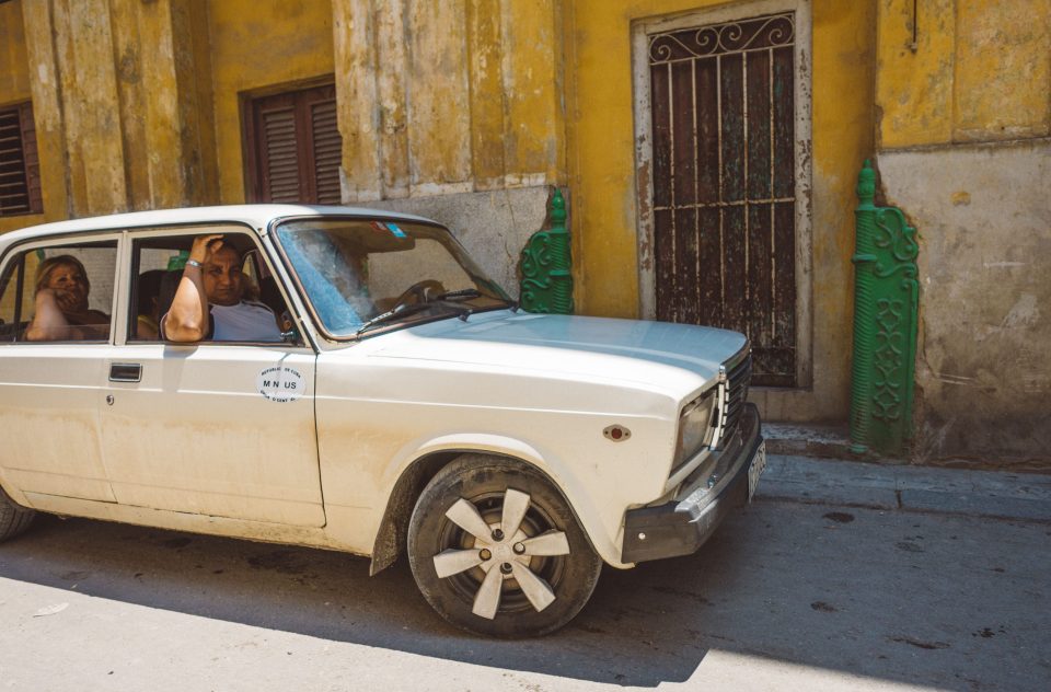 A Cuban family poses in their white classic car