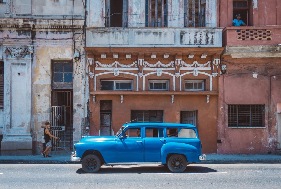 A vivid blue vintage car driving throgh Old Havana 