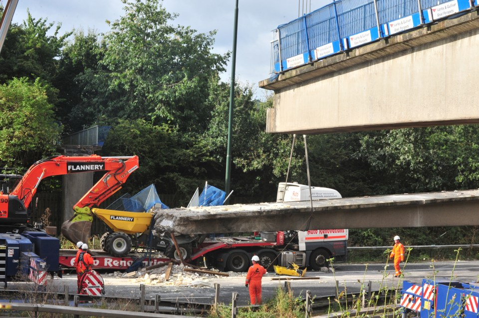 Smashed sections of the fallen bridge are loaded onto a giant transporter lorry