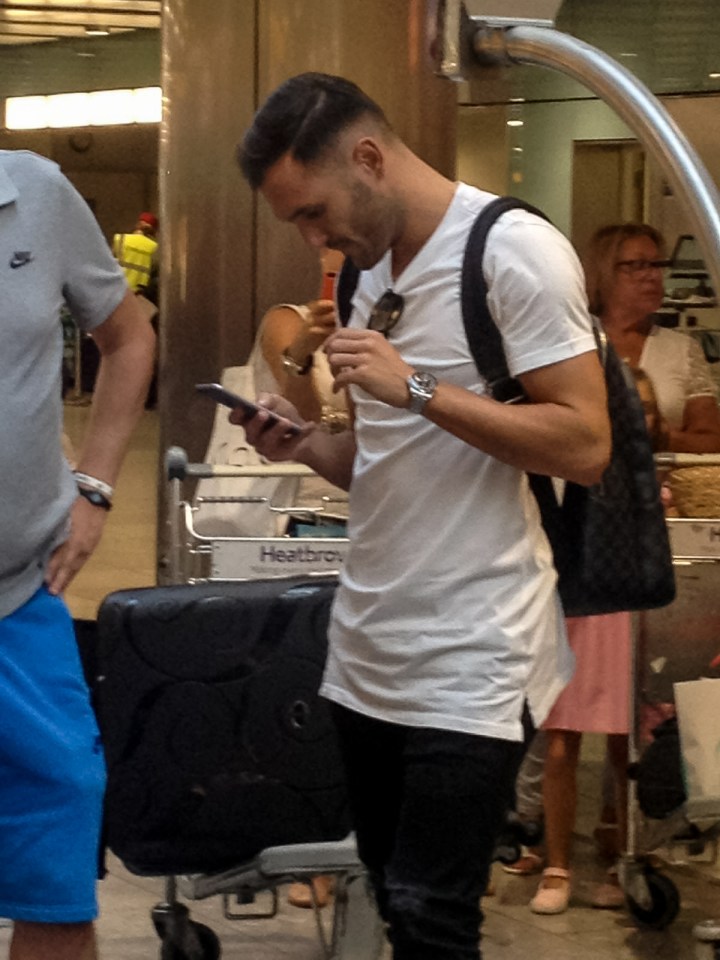 Lucas Perez checks his phone as he lands at Heathrow