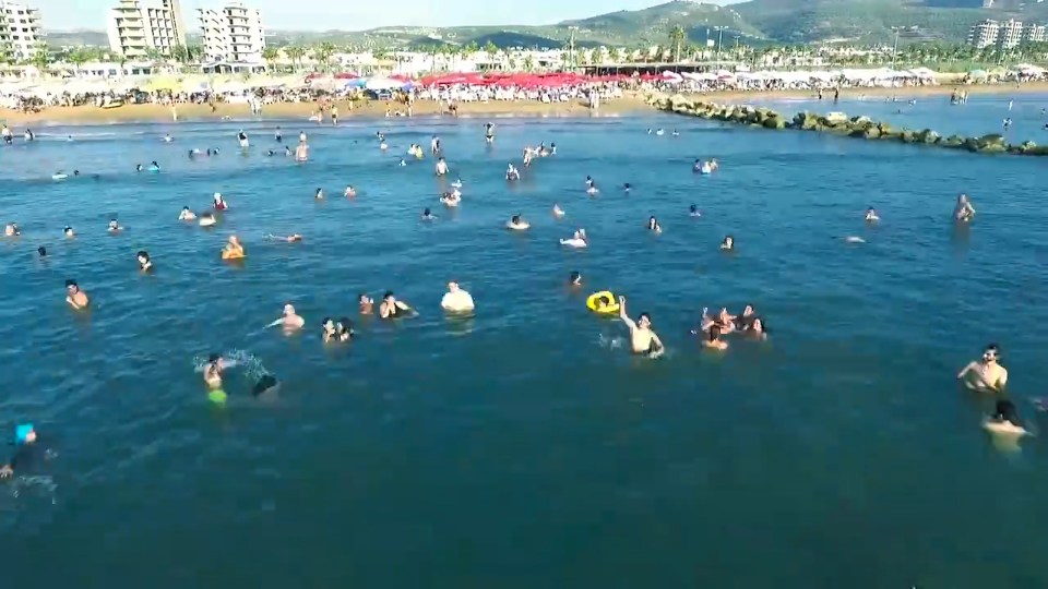  Bathers wave at the helicopter as it films along the picturesque coastline