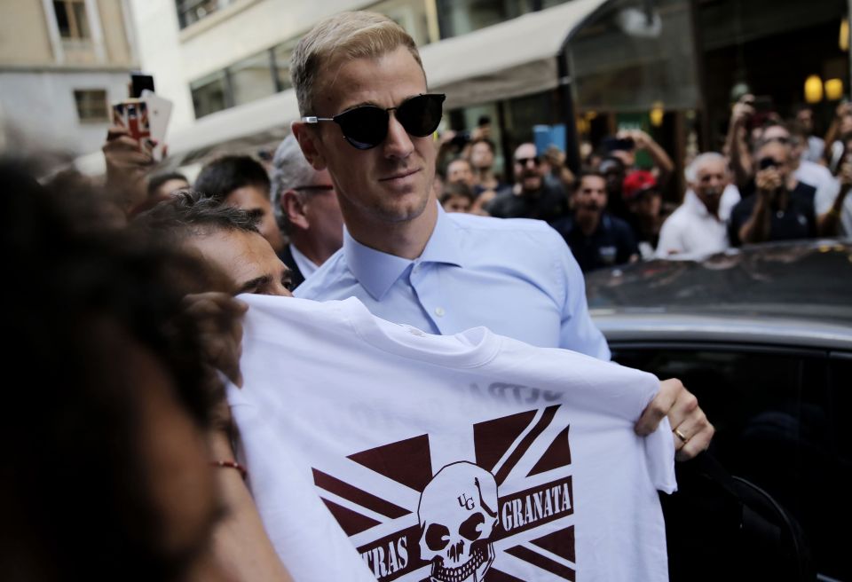 Joe Hart holds a supporter shirt as he arrives in Turin