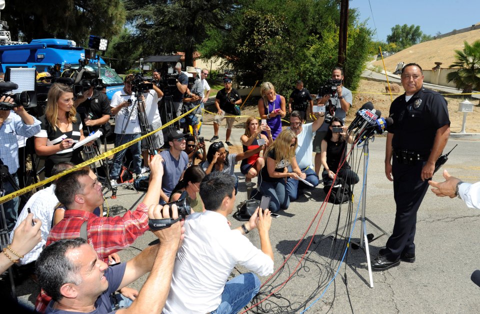  An LAPD officer briefs the media as they wait outside the home of rap star Brown