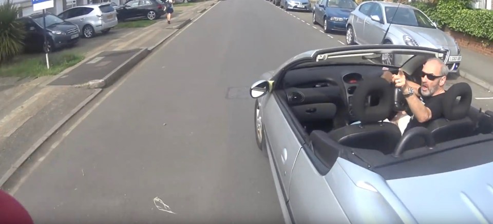 The motorist is seen gesturing towards the cyclist