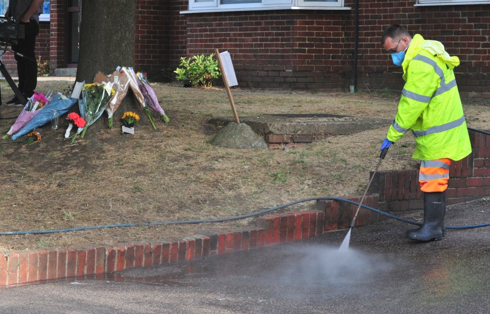 A workers sprays down the deadly crash site in south London