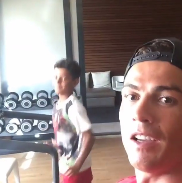 Cristiano Ronaldop on his exercise bike as his son runs alongside him