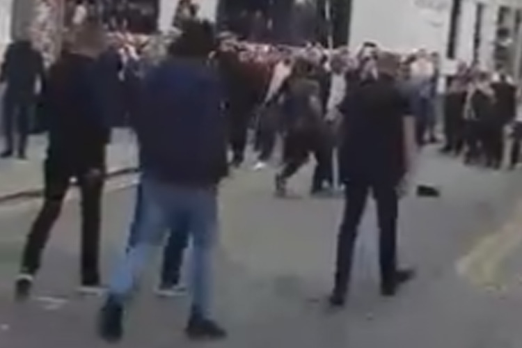 A group of men can bee seen approaching a much larger crowd in Manchester's Northern Quarter - popular for its bars, pubs and restaurants