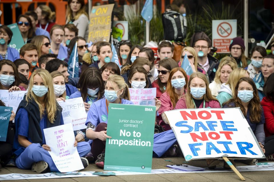  Junior doctors wear scrubs and masks as they sit down in a silent protest outside Bristol Royal Infirmary on the second day of all-out strike action during which they will provide no emergency care for patients in April