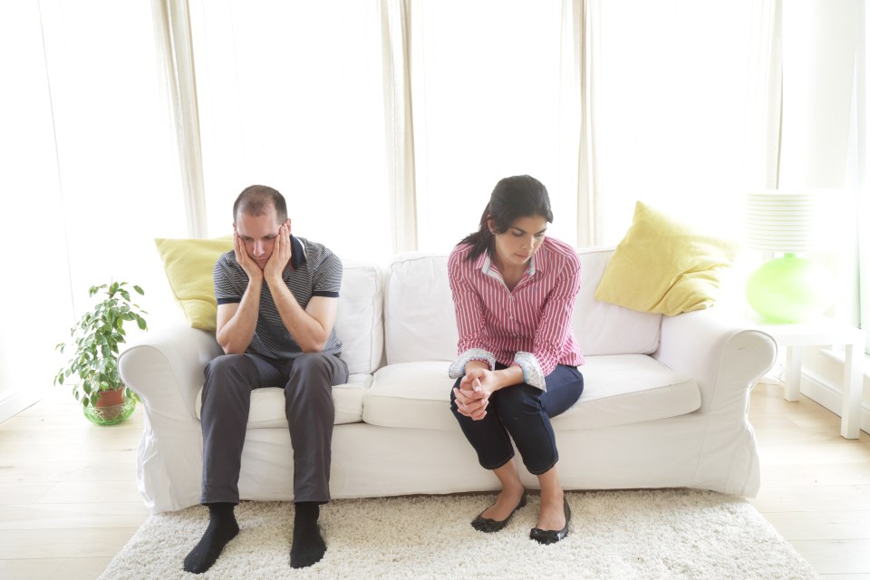 Couple sitting on the sofa looking gloom