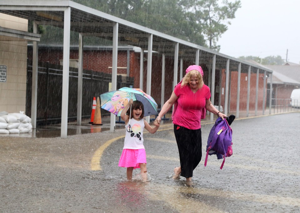  Ariel Callahan, 5, left, and her grandmother Kelly Smith, navigate rain water