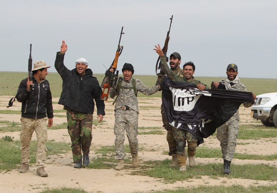  Iraqi Shiite fighters from the Popular Mobilisation units carry a seized ISIS flag