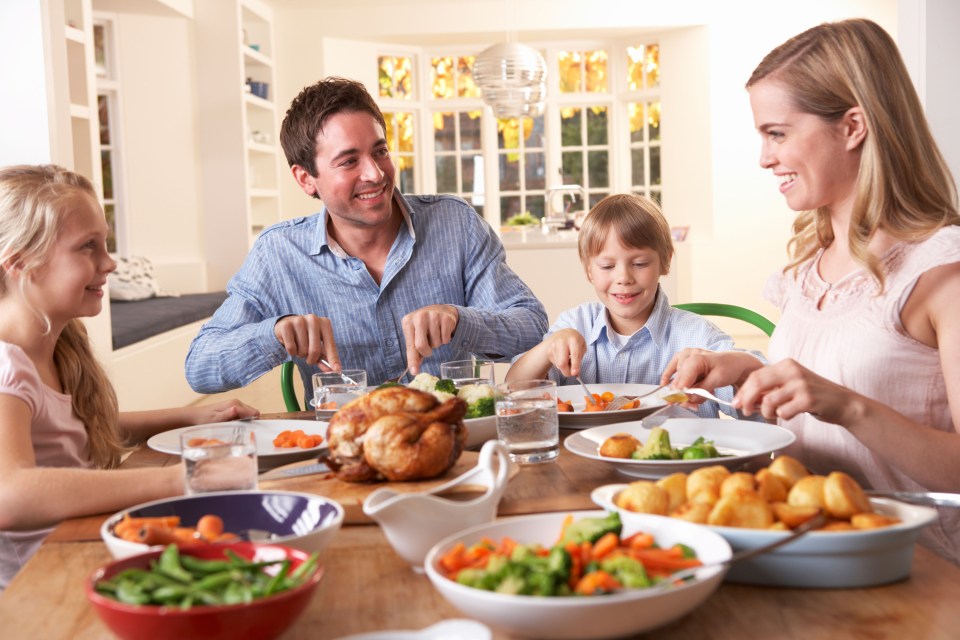 Happy family having roast chicken dinner at table