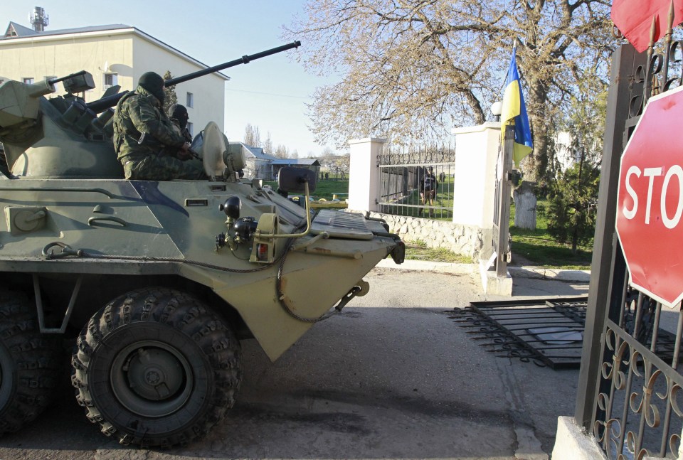 Armed men, believed to be Russian servicemen, drive an armoured vehicle onto the territory of a military airbase as they attempt to take over in the Crimean town of Belbek 