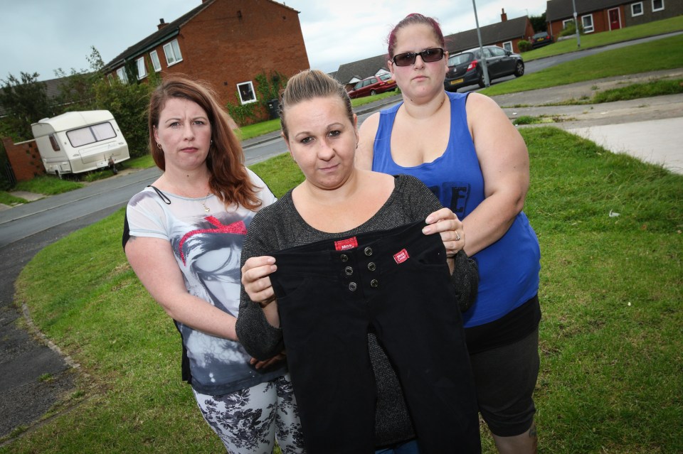 Tracey Webster, 40, (middle) holds up the trousers her 12-year-old daughter wore to school