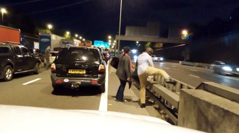 The couple can be seen stepping over the barriers to be able to cross the busy M25