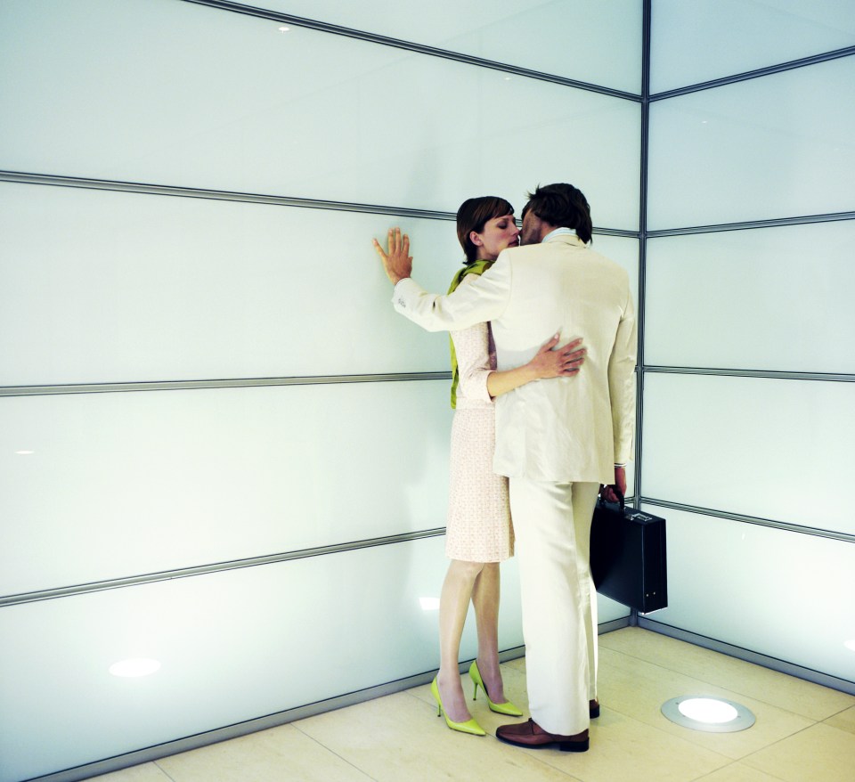 Young couple kissing by wall, man holding briefcase