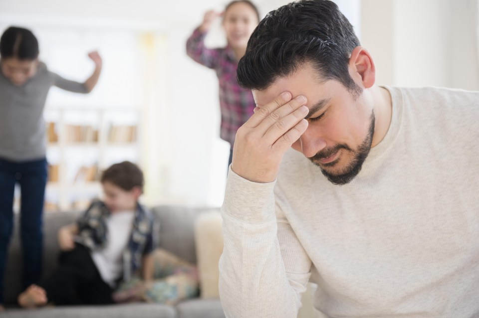 Stressed Caucasian father with shouting children in living room