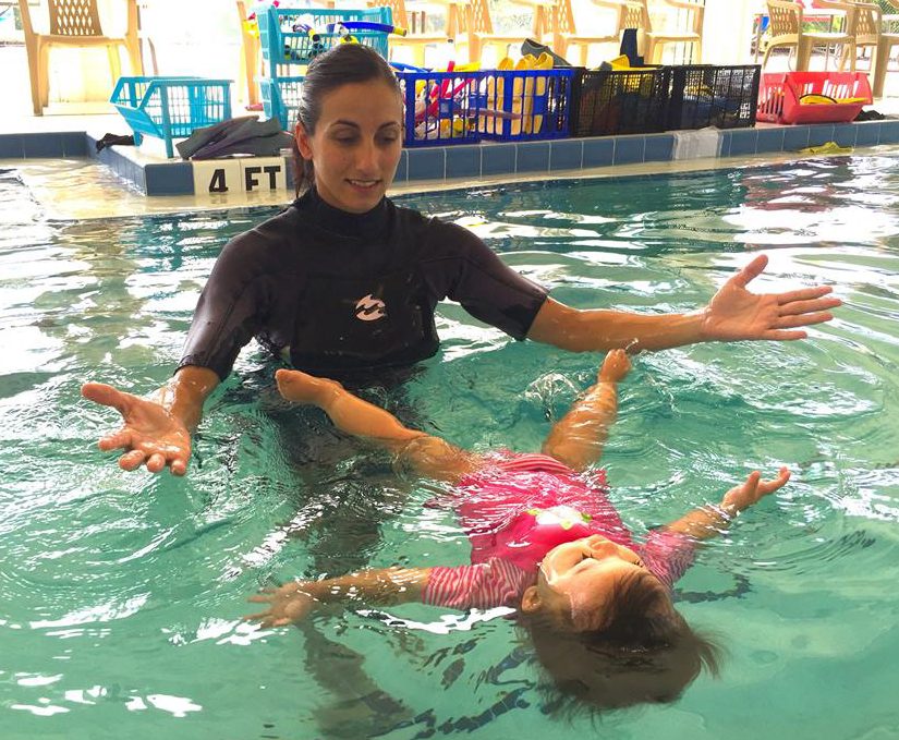  Silvia looks on as a little girl lies on her back in the water