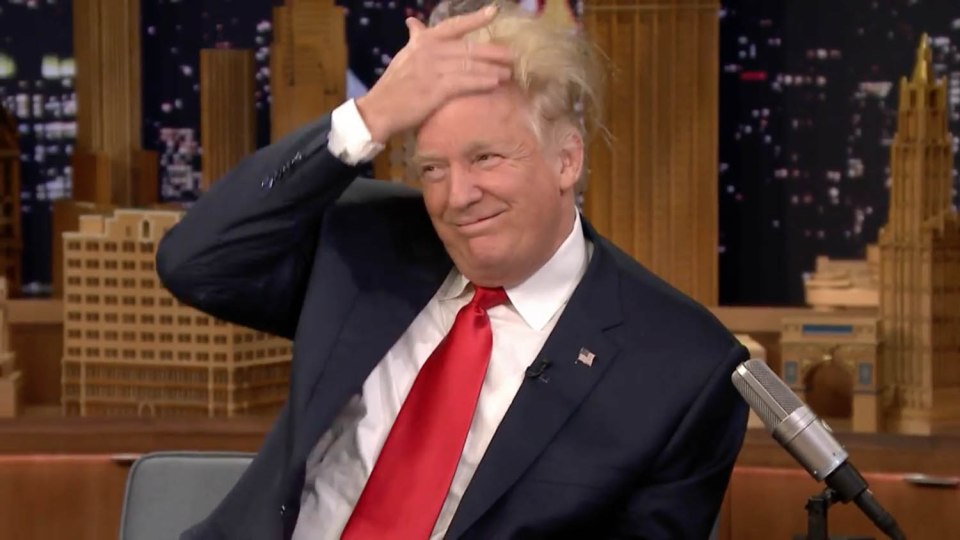 Trump tries to push his hair back in place but it resisted