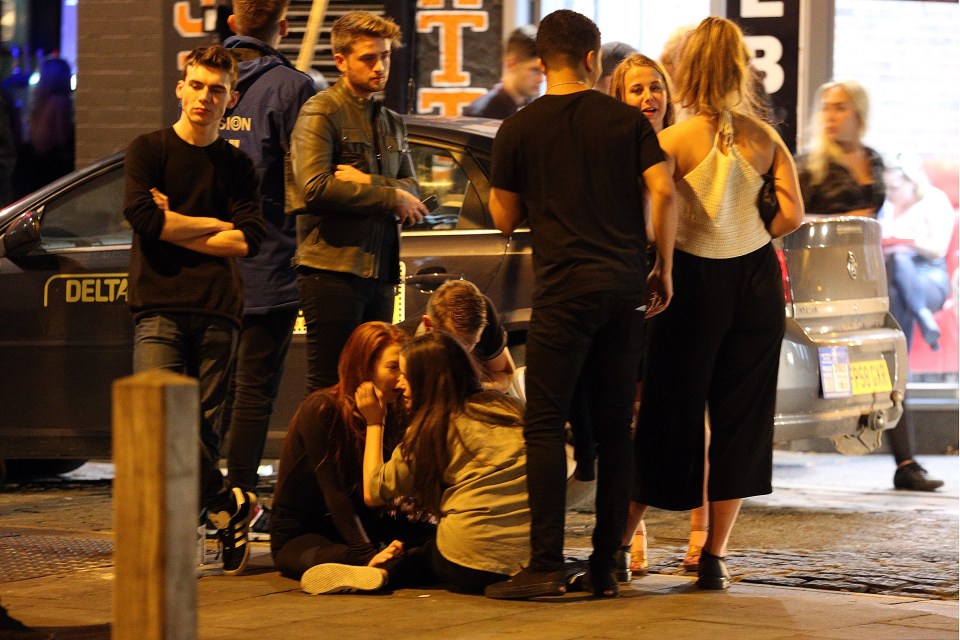  A group of youngsters sit down on the pavement after a long night out on the town in Liverpool