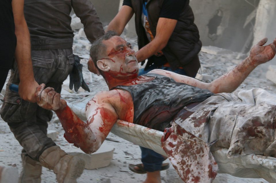 Carnage... a wounded man is carried from the rubble in Syrian city Aleppo