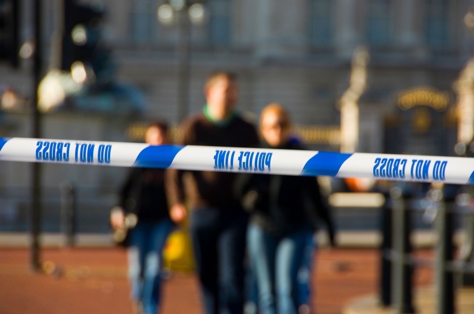 Do Not Cross, Police Line tape stretched across a road in central London with pedestrians in the background.