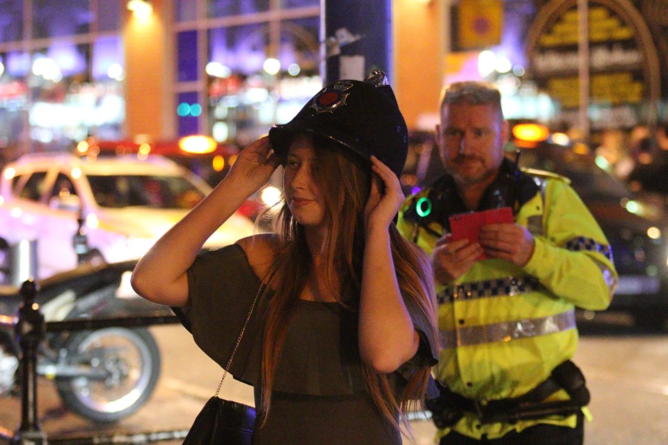  Reveller jokes with cops as she tries on an officer's helmet in Manchester