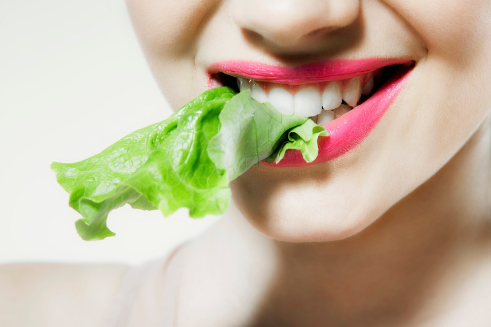 Young woman biting lettuce