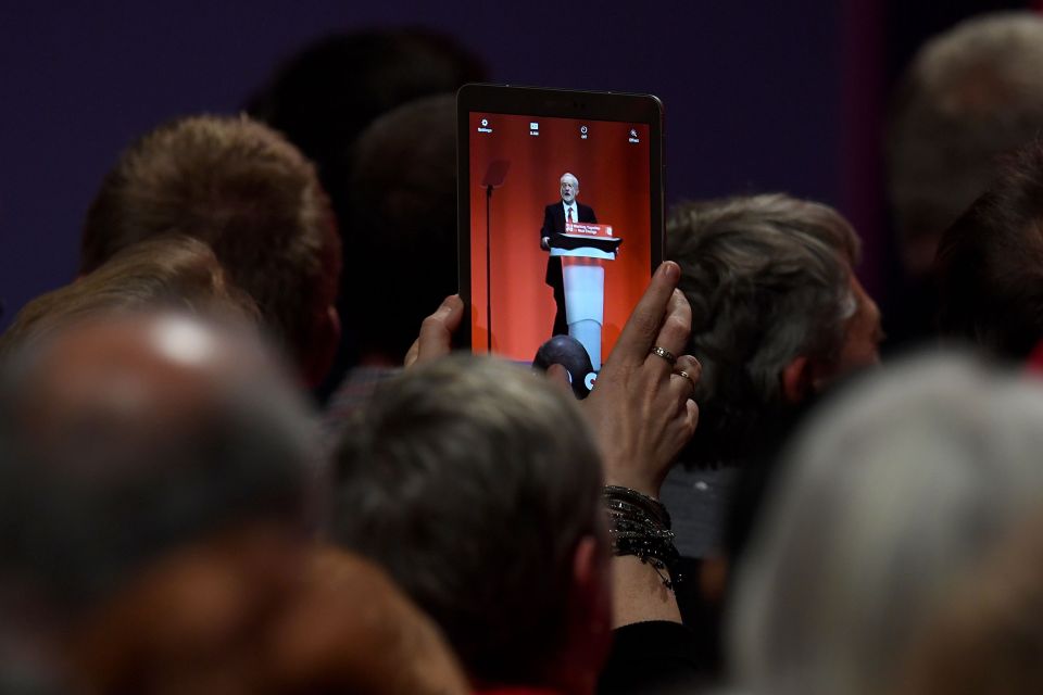  A delegate uses a tablet to take a picture of Labour leader Jeremy Corbyn as he delivered his keynote speech in Liverpool on the final day of his party's conference