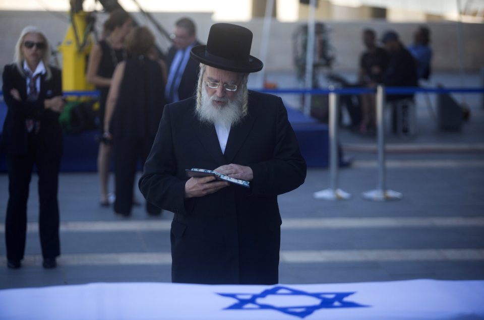 An Ultra-Orthodox Jewish man prays next to the coffin of Shimon Peres