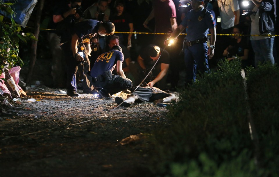 Cops examine the body of one of the three suspects killed in an alleged 'buy-bust' operation