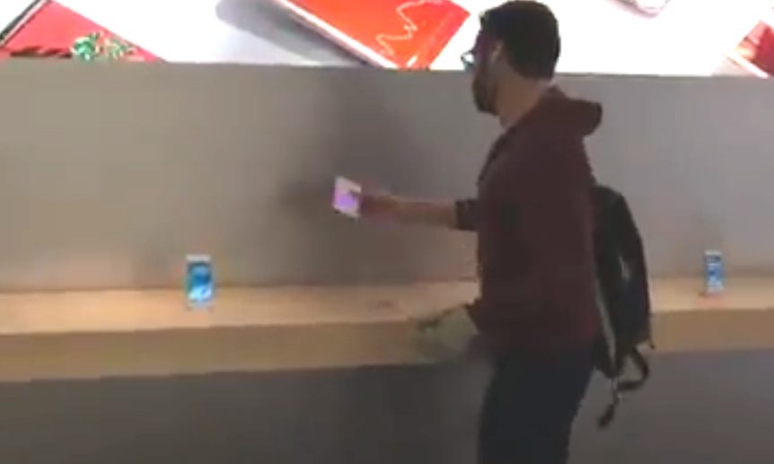  The man walks around the Apple store picking up iPhones before smashing them against a table