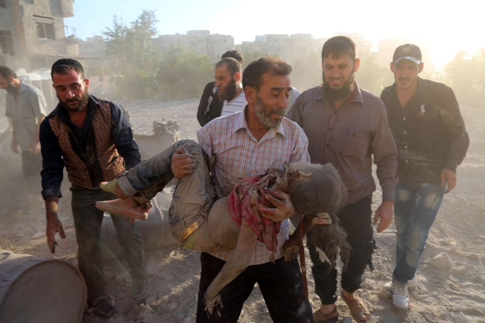 A Syrian man carries the body of a girl