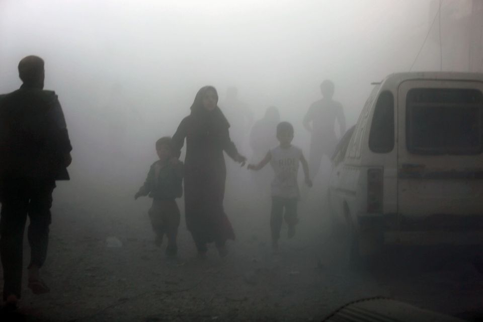 Syrians emerge from a dust cloud followi