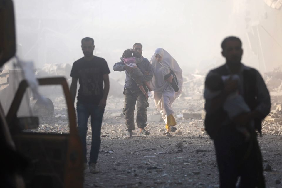 Syrians emerge from a dust cloud followi