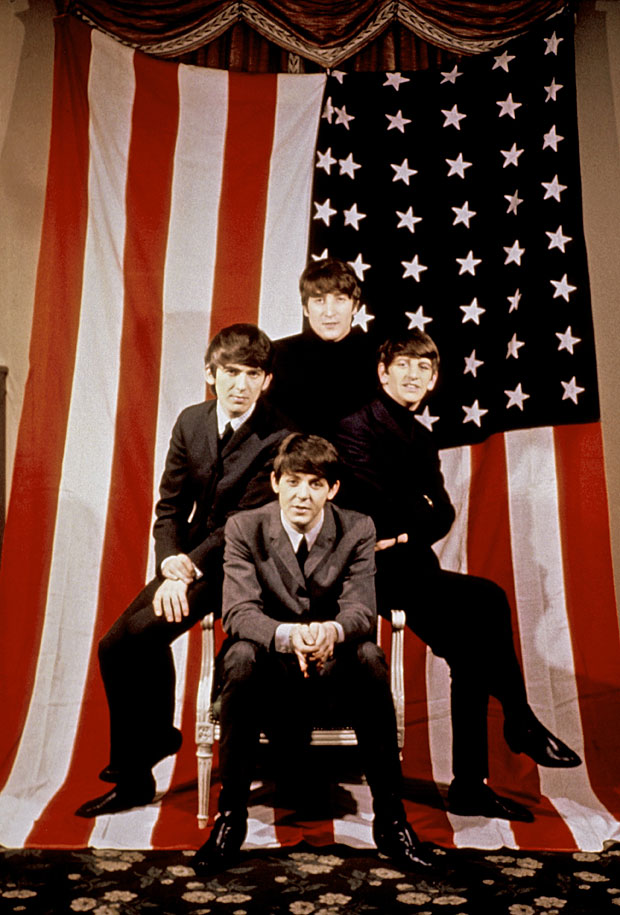  John, Paul, George and Ringo pose in front of the Stars and Stripes after arriving in New York in 1964.