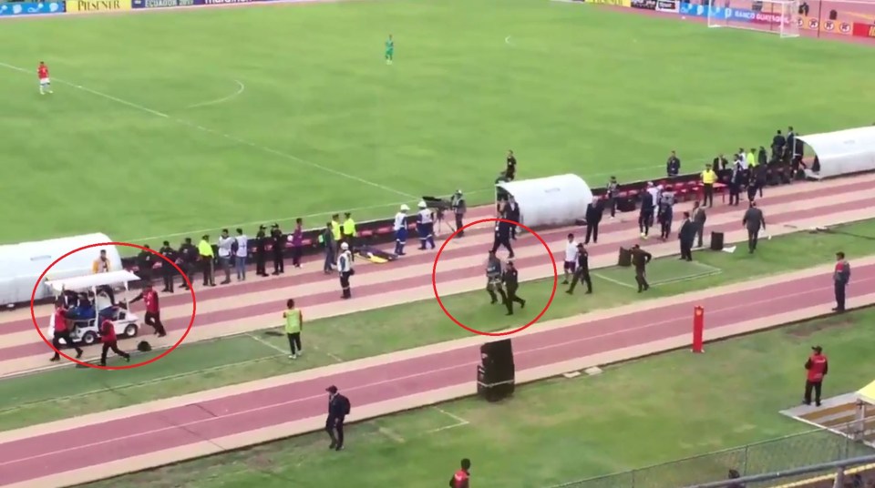  Enner Valencia is taken away on a stretcher as police follow closely in full view of the crod at the Estadio Olimpico Atahualpa in Quito