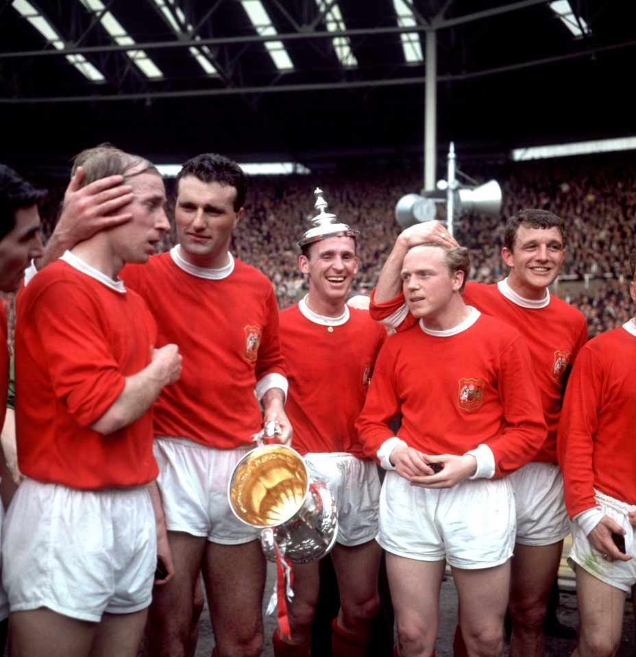 Manchester United captain Noel Cantwell (third left) tells teammate Bobby Charlton (second left) to cheer up as the United players celebrate with the trophy: (left to right) Tony Dunne, Bobby Charlton, Noel Cantwell, Pat Crerand, Albert Quixall and David Herd