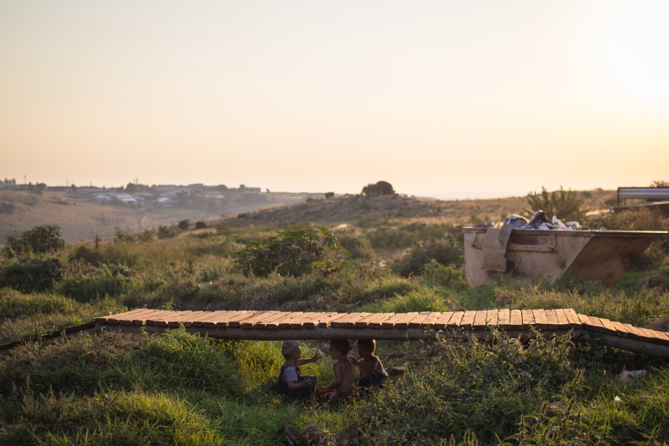  Children play under a makeshift bridge near the refuse dump by the entrance of the white squatter camp in Munsieville