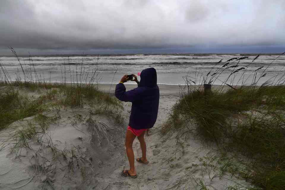 A local woman takes pictures on the beach while trying to stay standing