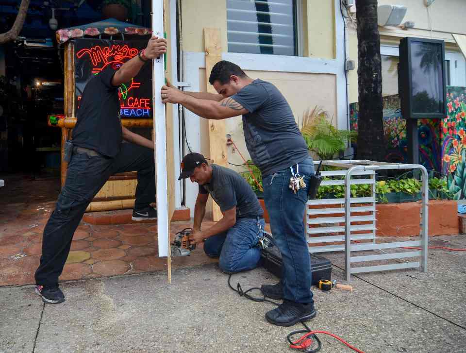 Maintenance workers at Mangos Tropical Cafe on Ocean Drive attach plywood on the entrance 