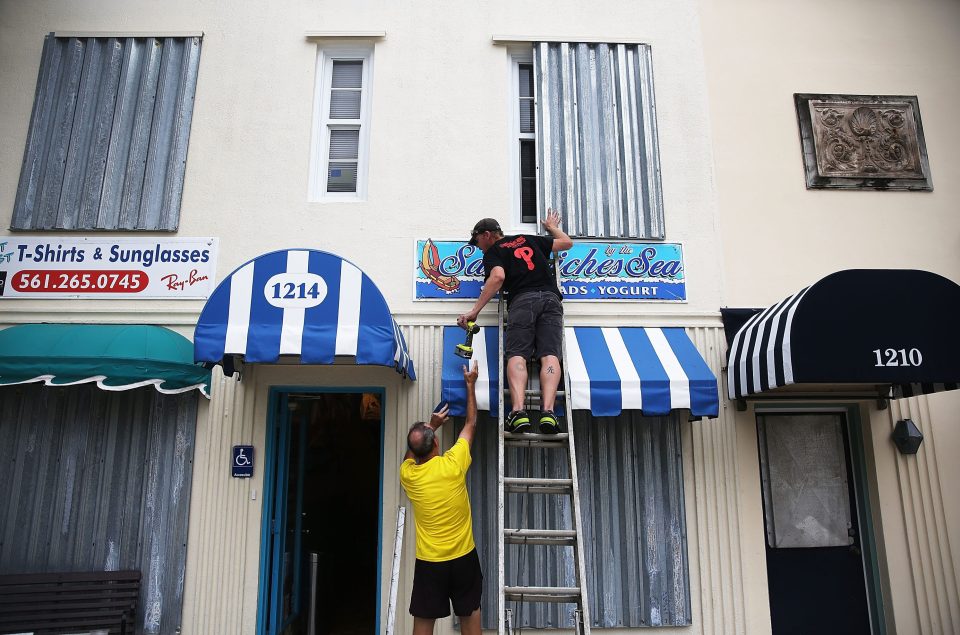 Danny Askins and Brenden Kavana (right) put up hurricane shutters as they prepare the Sandwiches Sea restaurant for the impending storm