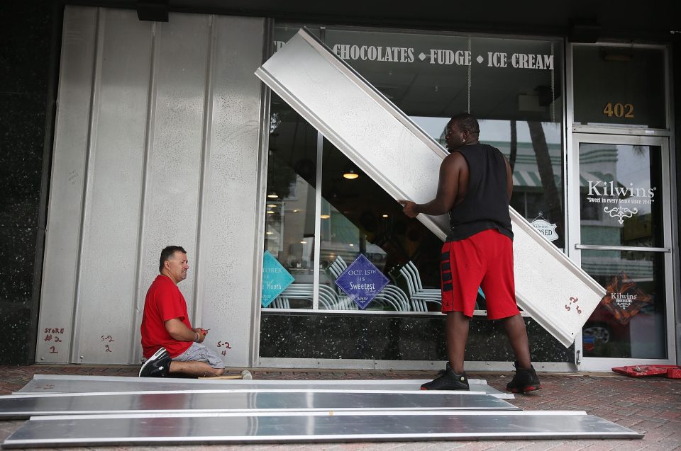 Jason Brock (left) and Kevin Hunter put up hurricane shutters in front of a business